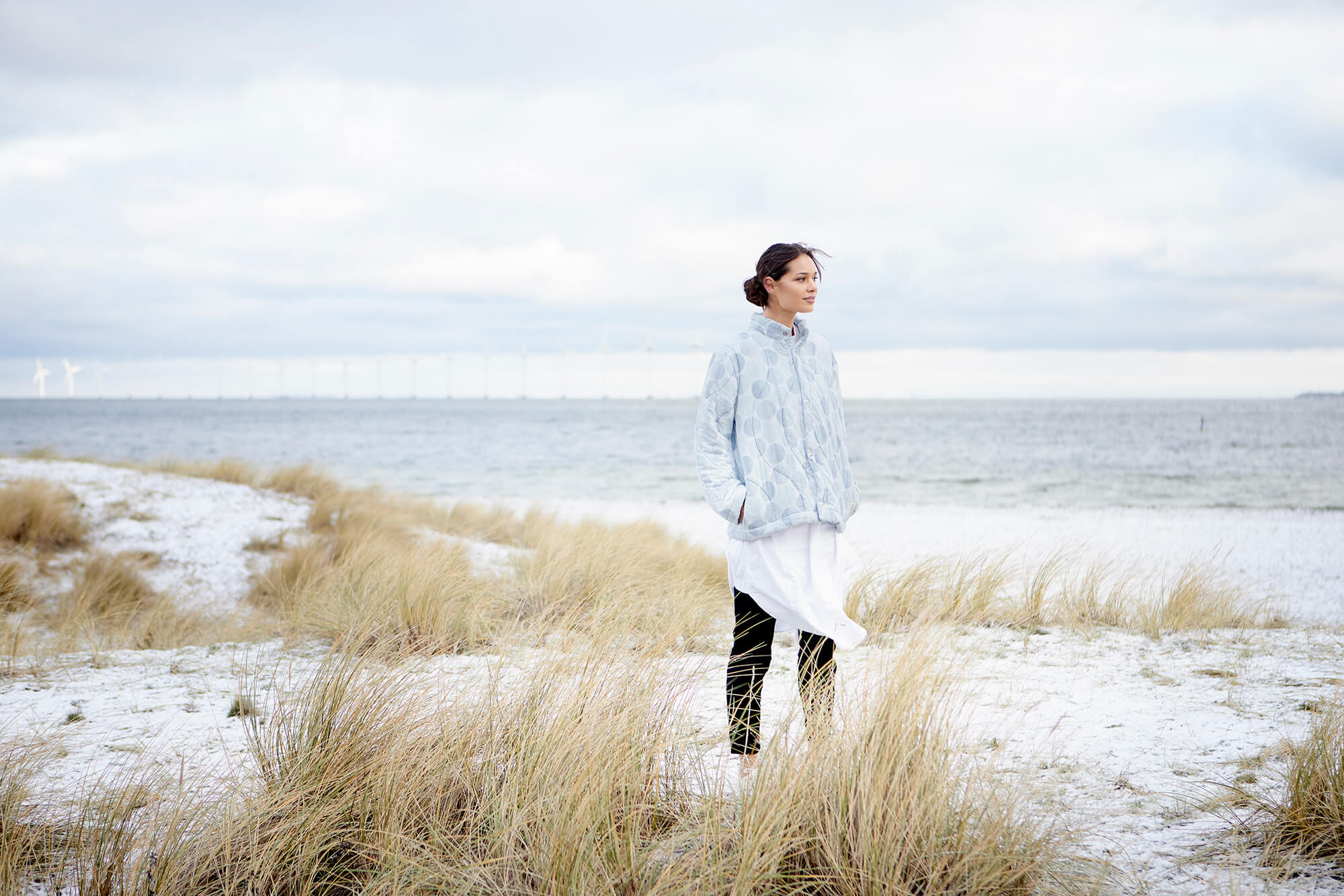 Kvinde på strand i textilia upcy jakke
